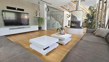 Geräumiges Wohnzimmer mit modernem Kamin, Holzboden und Zugang zu einer Treppe.