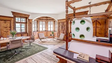 Geräumiges Zimmer mit traditioneller Holzvertäfelung, Erker und markantem Kachelofen, hell und einladend.