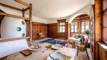 Traditioneller Wohn- und Essbereich mit Holztäfelung, Kachelofen und gemütlicher Sitzecke am Erkerfenster.