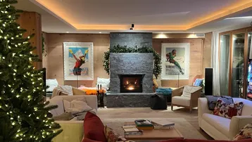 Gemütliches Wohnzimmer mit Kamin, Weihnachtsbaum und indirekter Beleuchtung.