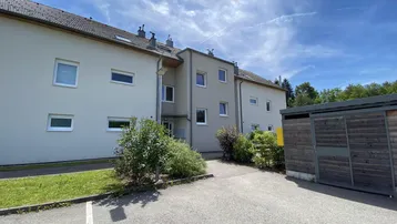 Ansicht der modernen Wohnanlage mit gepflegter Fassade und Eingangsbereich unter blauem Himmel.