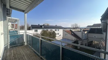 Balkon mit Holzboden und Metallgeländer, bietet einen weiten Blick über die umliegenden Gebäude.