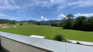 Panoramablick von der Dachterrasse über weite grüne Felder und die umliegende Berglandschaft.