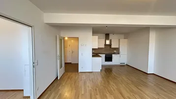 Heller offener Wohnbereich mit Holzboden und integrierter Küche in modernem Stil.