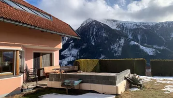 Hausfassade mit Terrasse und beeindruckendem Blick auf die schneebedeckten Berge.