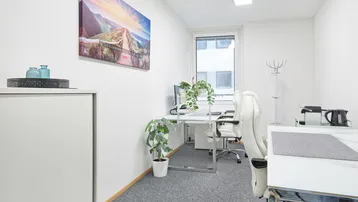 Helles und modernes Büro mit einem Schreibtisch, Bürostuhl und Pflanzen, ideal für konzentriertes Arbeiten.