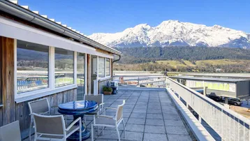 Geräumige Terrasse mit Sitzgelegenheiten und atemberaubendem Blick auf die schneebedeckten Berge.