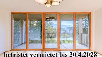 Heller Raum mit großen Fenstern, die auf einen Balkon führen und einen weiten Blick bieten.