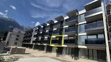 Moderne Wohnanlage im Bau mit Balkonen und Bergblick, umgeben von einer Baustelle.