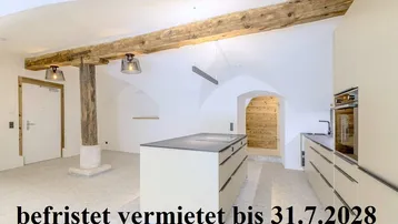 Moderne Küche mit Kücheninsel, Gewölbedecken und freiliegenden Holzbalken in einem historischen Ambiente.