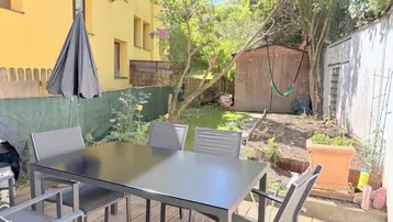 Gemütlicher Gartenbereich mit Holzboden, Esstisch und Gartenhaus, ideal für entspannte Stunden im Freien.
