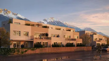 Moderne Wohnanlage mit Balkonen und Terrassen vor alpiner Bergkulisse bei Sonnenuntergang.