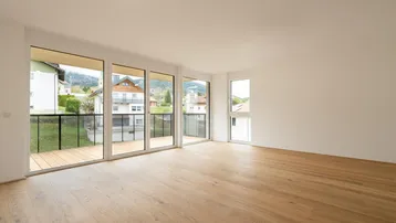 Heller Wohnraum mit Eichenparkettboden, großen Fenstern und Zugang zu einem Balkon mit Bergblick.