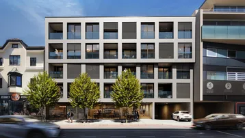 Moderne Wohn- und Geschäftshausfassade mit großen Fenstern, Balkonen und integrierter Tiefgarage in urbaner Umgebung.