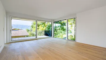 Helles Zimmer mit Holzboden, großen Fenstern und Zugang zu einem Balkon mit Bergblick.