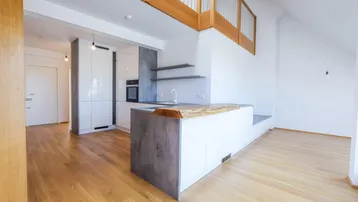 Moderne offene Küche mit Holzboden, weißen Schränken und einer Holztheke in einem hellen Raum.
