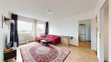 Helles Wohnzimmer mit rotem Ecksofa, Teppich und großen Dachfenstern, die viel Licht hereinlassen.