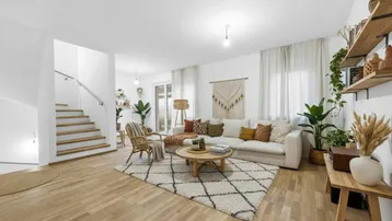 Helles und modern eingerichtetes Wohnzimmer mit Holzboden, bequemer Couch und vielen Pflanzen.