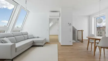 Heller, moderner Wohn-Essbereich in einer Dachgeschosswohnung mit großen Dachfenstern, Holzboden und Klimaanlage.