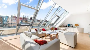 Helles Wohnzimmer mit großen Dachfenstern, Holzboden und moderner Couchgarnitur.