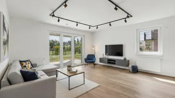 Helles Wohnzimmer mit modernem Design, Parkettboden und Zugang zum Gartenbereich.