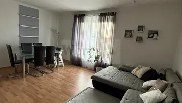 Heller Wohn- und Essbereich mit Ecksofa, Esstisch und Parkettboden.