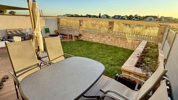 Gemütliche Terrasse mit Holzboden, Esstisch und Blick auf den Garten und die Umgebung.