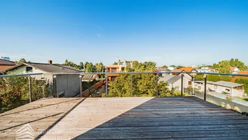 Große Holzterrasse mit Glasgeländer und weitem Blick über die umliegende Nachbarschaft.