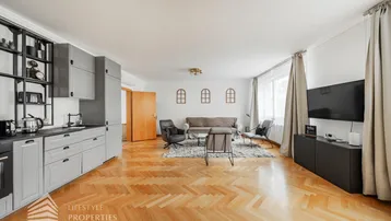 Geräumiger offener Wohnbereich mit integrierter Küche, Parkettboden und viel Tageslicht.