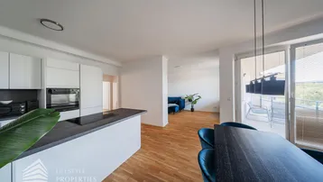 Moderner offener Wohn-Essbereich mit integrierter Küche, Holzboden und Zugang zum Balkon.