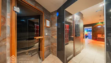 Eingangsbereich zu einer modernen Sauna mit Holztür und Umkleideschränken in einem Wellnessbereich.