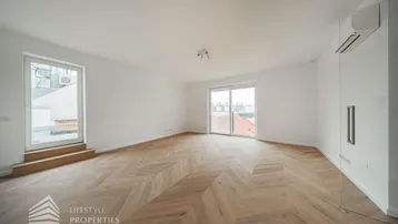 Helles, leeres Zimmer mit modernem Fischgrätparkett und Zugang zu einer Terrasse.