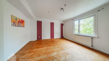 Helles Wohnzimmer mit Fischgrätparkettboden, großen Fenstern und dekorativen Wandstreifen.
