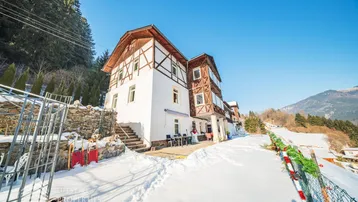 Seitenansicht des Gebäudes mit traditioneller Holzfassade und verschneiter Umgebung.