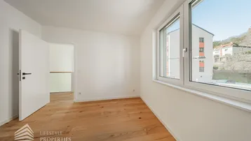 Schlafzimmer mit Holzdielenboden und weitem Blick aus dem Fenster auf die Umgebung.