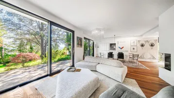 Helles, offenes Wohn- und Esszimmer mit großen Fenstern, Holzboden und modernem Design.