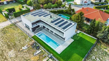 Moderne Villa mit Flachdach, Pool und Photovoltaikanlage in grüner Umgebung.