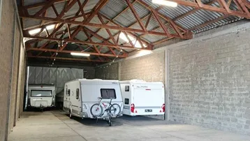 Geräumige Lagerhalle mit hohen Decken, sichtbaren Holzbalken und Betonboden, ideal für Wohnwagen.