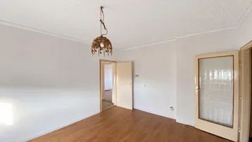 Helles Zimmer mit Holzpaneeldecke und Laminatboden, bereit zur individuellen Gestaltung.