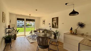 Heller, offener Wohn-Essbereich mit Holzboden, moderner Einrichtung und Zugang zum Garten.