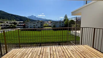 Geräumiger Balkon mit Holzboden und weitem Blick auf die Berge und grüne Umgebung.