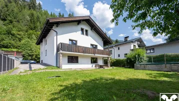 Freistehendes Haus mit großem Garten, Balkon und Bergblick in grüner Umgebung.