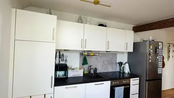 Funktionale Küche mit weißen Schränken, schwarzer Arbeitsplatte und integrierten Geräten, ideal für den täglichen Gebrauch.