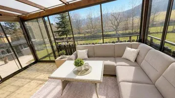 Heller Wintergarten mit bequemer Sitzecke und weitem Blick ins Grüne.