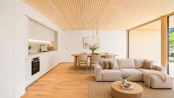 Moderner offener Wohn-Essbereich mit integrierter Küche, Holzboden und Zugang zur Terrasse.