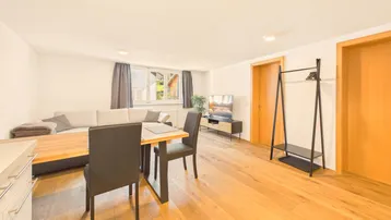 Helles Wohn- und Esszimmer mit Holzboden, bequemer Sitzecke und Esstisch für gesellige Stunden.