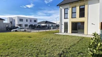 Neubau-Doppelhaushälfte mit frisch angelegtem Rasen und sonnigem Gartenbereich.