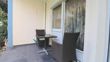Gemütlicher Sitzbereich auf der Terrasse mit Rattanmöbeln und Blick ins Grüne.