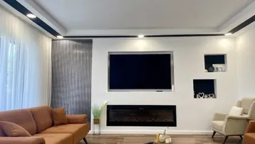 Geräumiges Wohnzimmer mit modernem Design, großem Sofa und integriertem Elektrokamin.