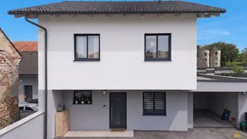 Modernes Einfamilienhaus mit weißer Fassade, dunklem Dach und integriertem Carport.